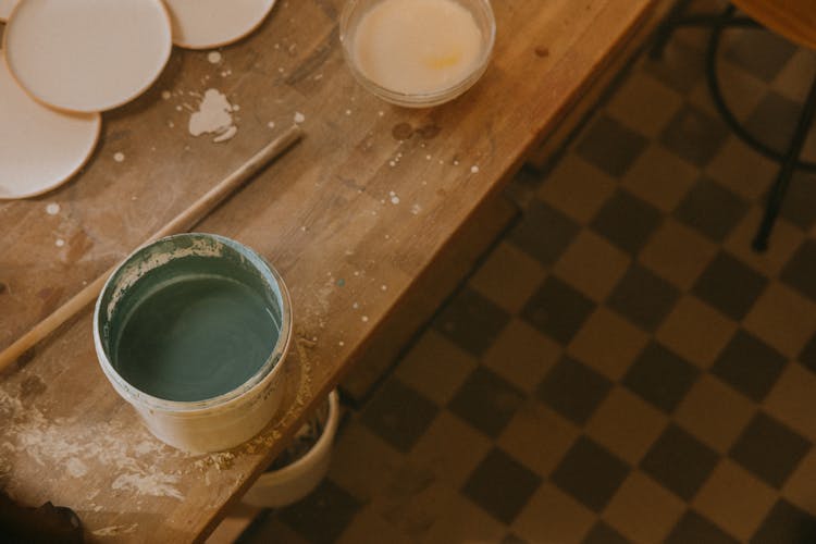 A Pale With Paint On A Wooden Surface