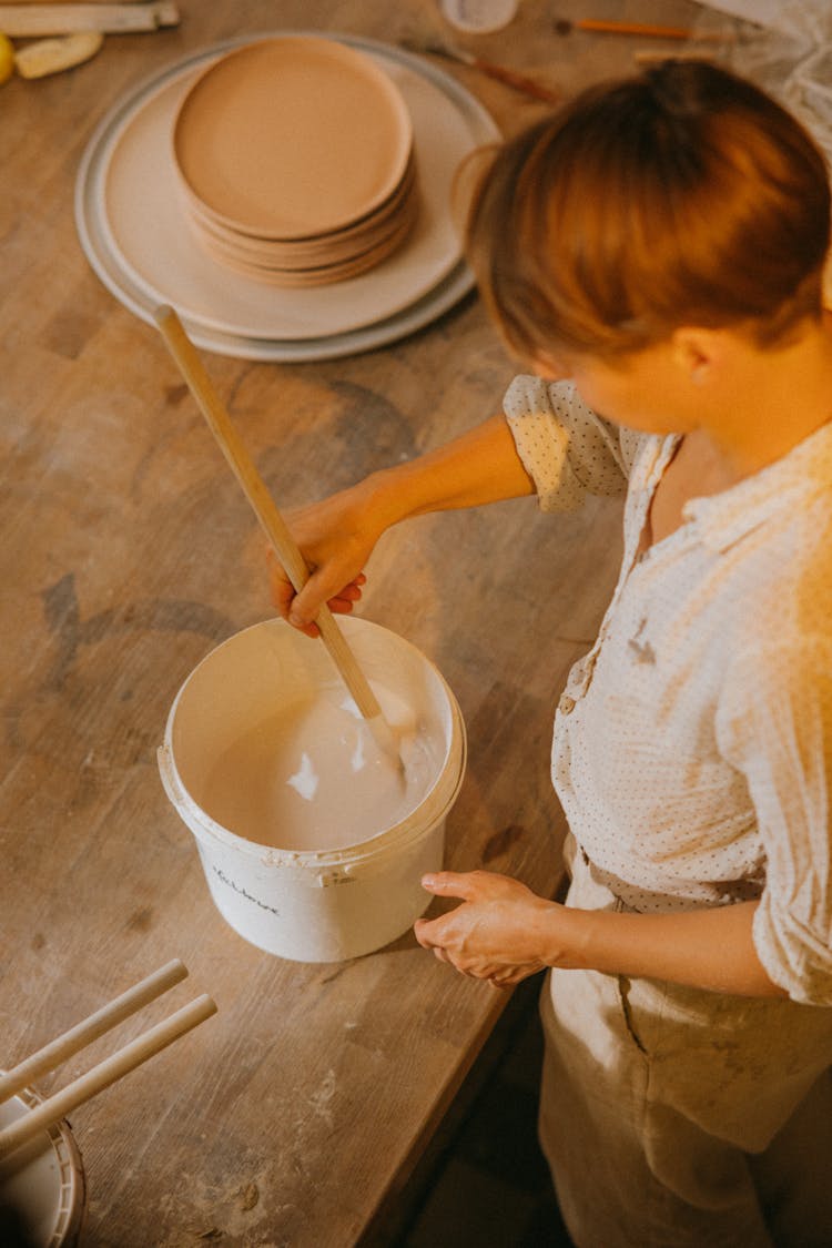 A Person Mixing Paint In A Bucket