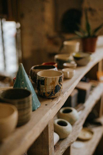 Photo by KoolShooters on Pexels An array of handmade pottery cups and bowls on a rustic wooden shelf, capturing an earthy and artistic vibe.