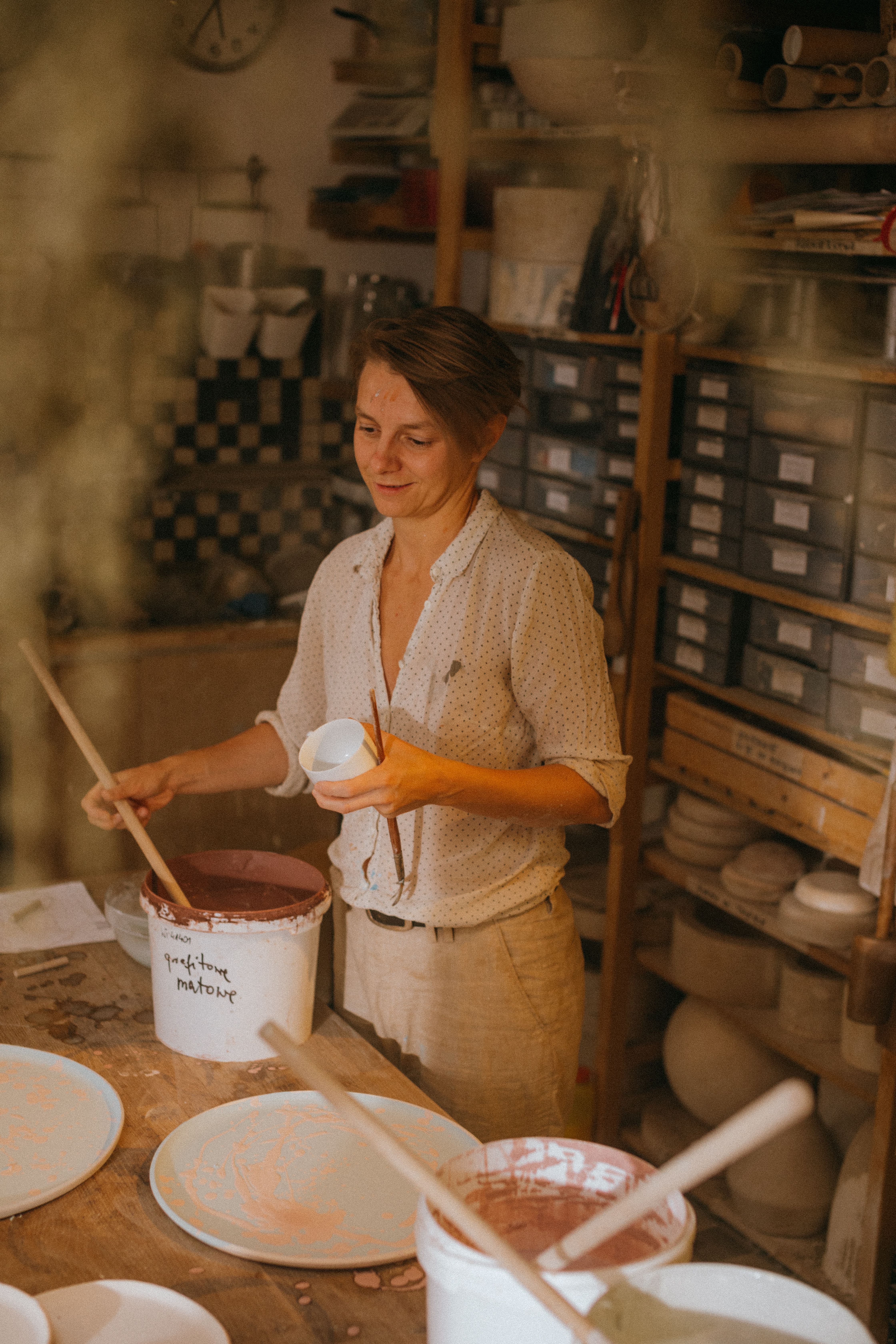 A potter in a warm-lit studio working on clay pottery, showcasing traditional arts and crafts.