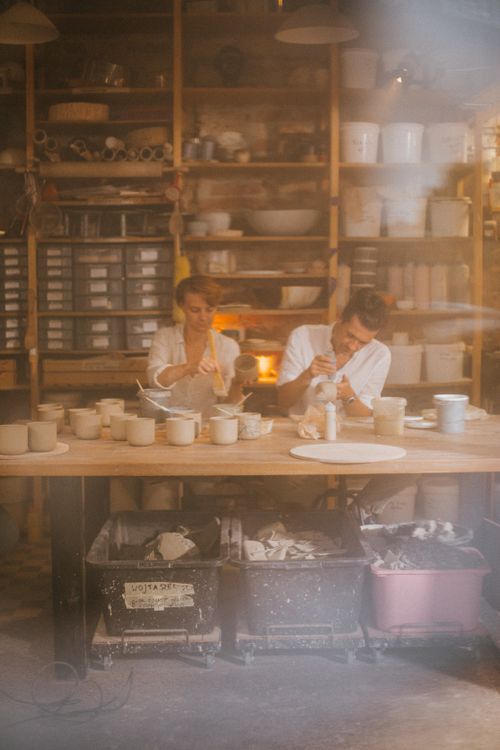 Free Two ceramic artists crafting pottery in a well-lit workshop, surrounded by tools and materials. Stock Photo