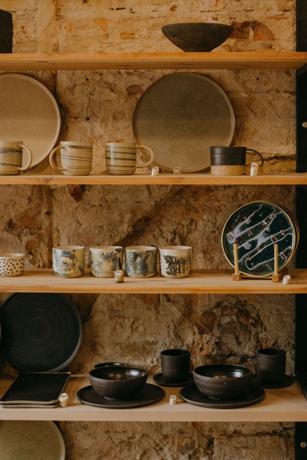 Finished dishes on wooden shelves against a brick wall