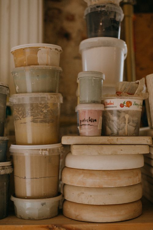 Free Assorted containers filled with creamy materials stacked in a workshop setting. Stock Photo