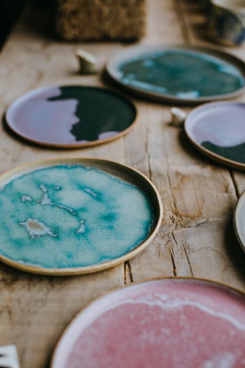 Free Close-up of colorful ceramic plates on a rustic wooden table, showcasing artistic glazing. Stock Photo