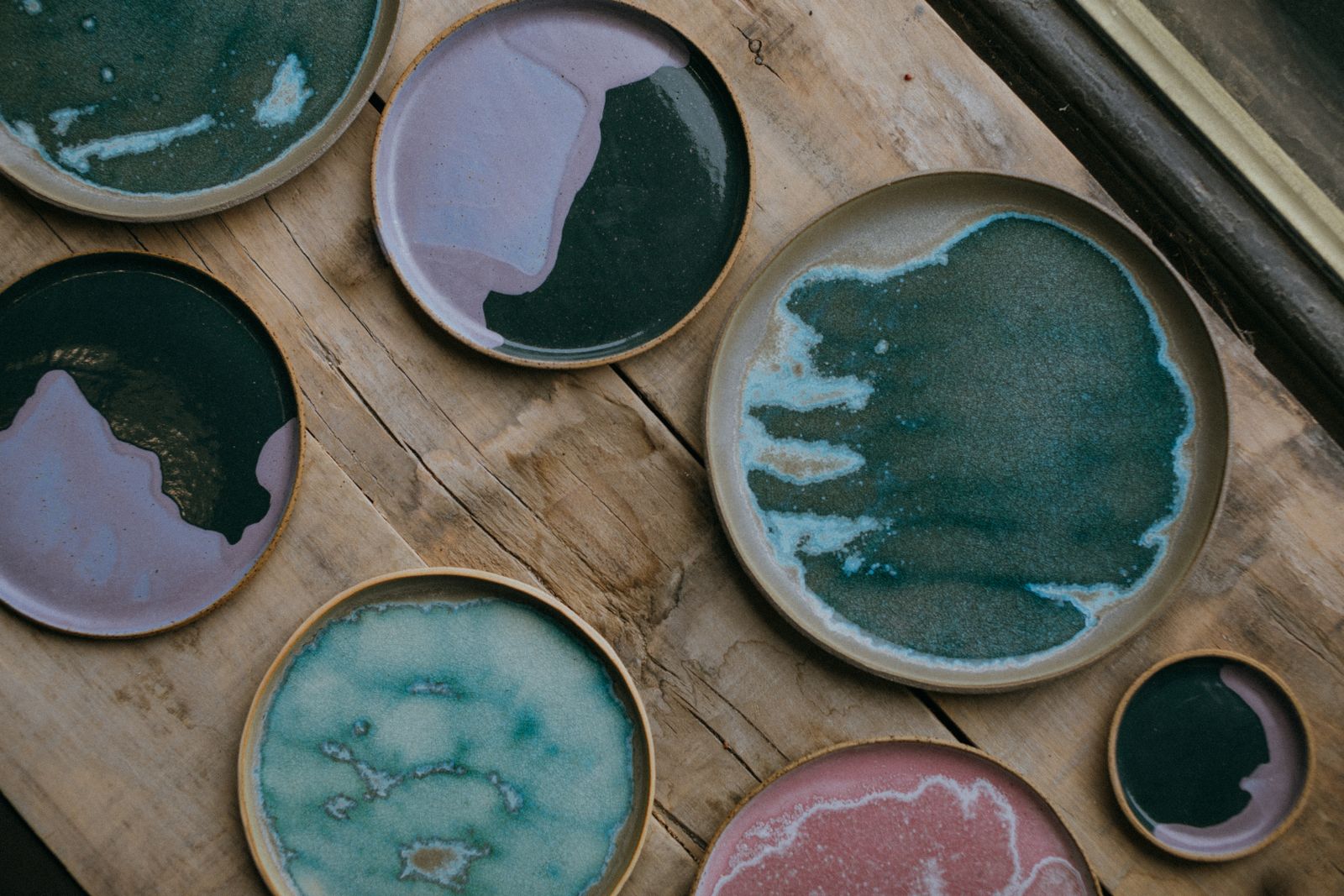 Hand-glazed stoneware plates laid out on a weathered workbench — photo by KoolShooters on Pexels
