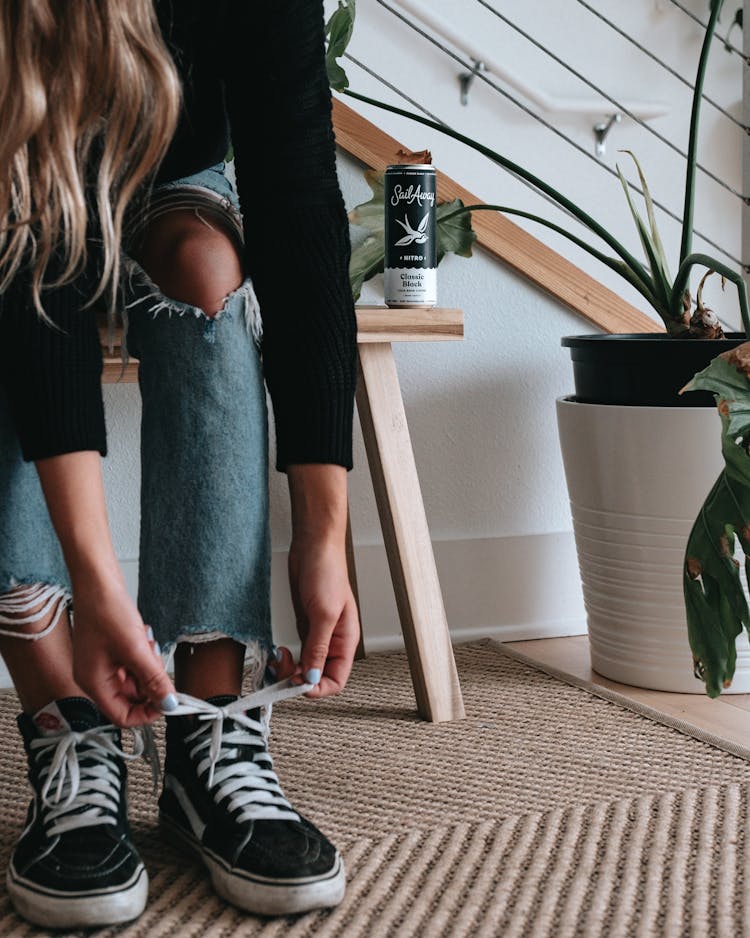 Close-up Photo Of Woman Tying Shoelaces On Her Black Shoes 