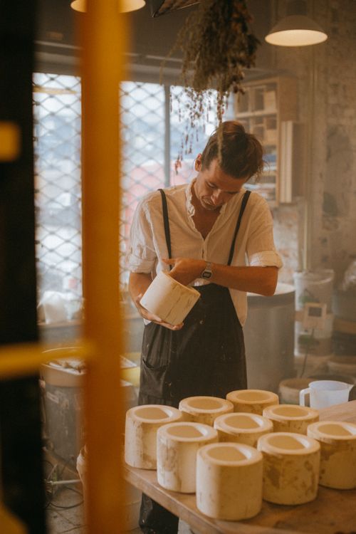 Free An artisan meticulously working on pottery in a cozy indoor workshop setting. Stock Photo