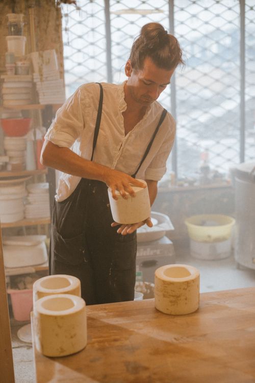 Free A potter in a workshop creating pottery, surrounded by clayware and tools. Stock Photo