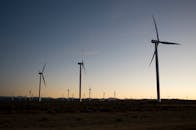 在乡村宁静的日落天空下，风力涡轮机创造着可再生能源