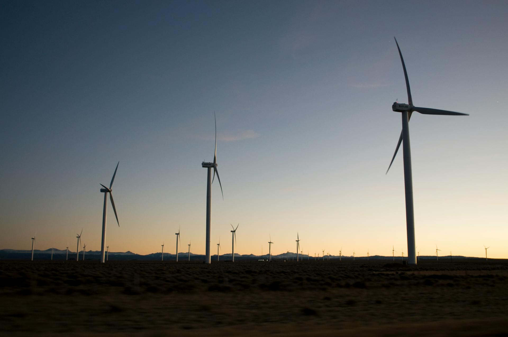 Wind turbines creating renewable energy under a serene sunset sky over a rural landscape.