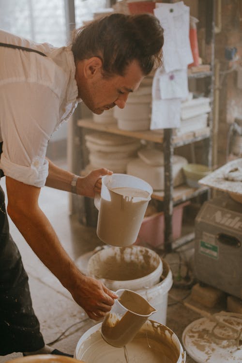 Craftsman holding Pitchers of Clay Liquids 