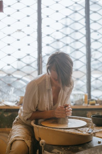 Potter shaping clay in a sunlit studio — photo by KoolShooters on Pexels