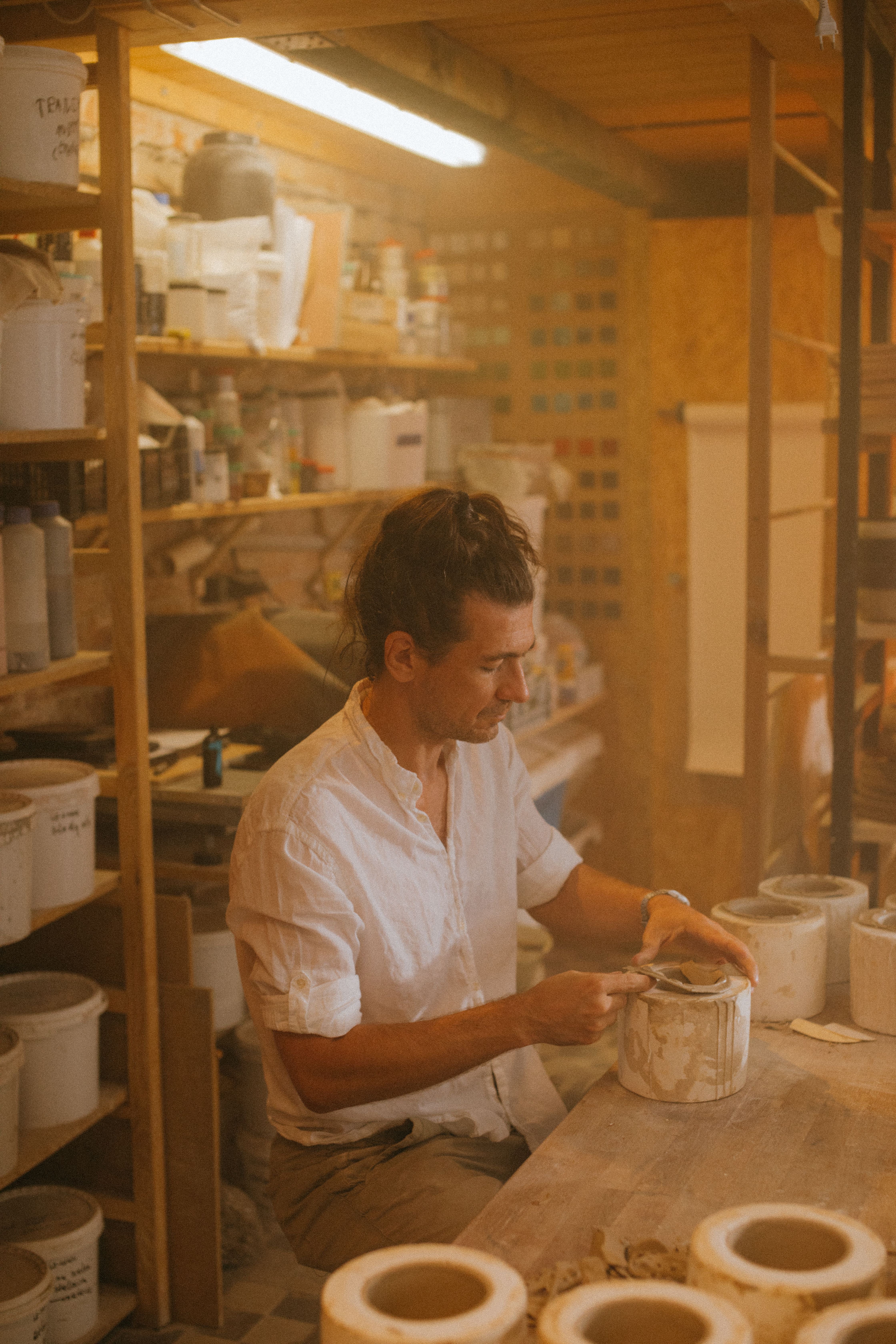 Focused artisan skillfully crafting ceramics in a warm-lit workshop environment.