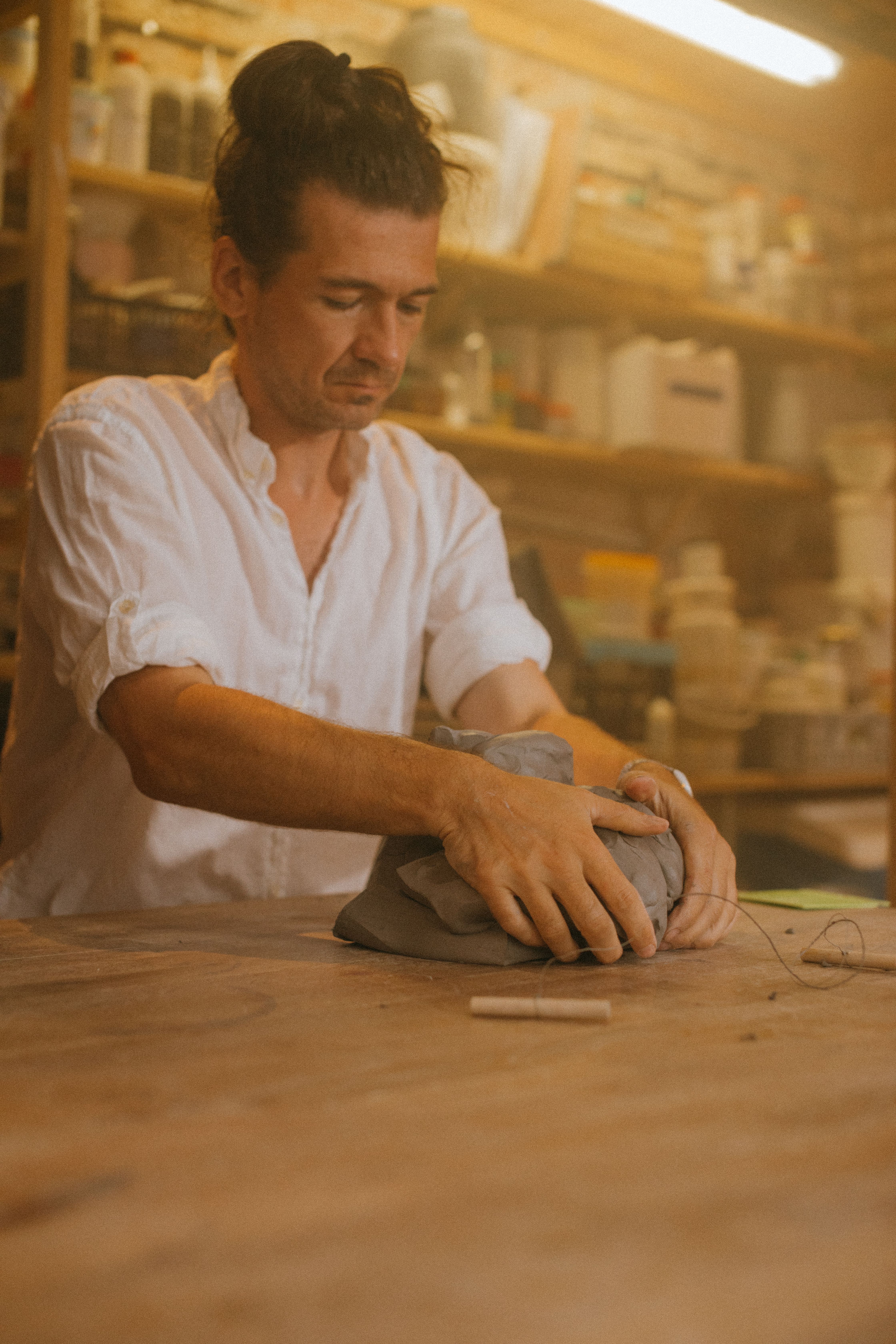 A skilled craftsman molds clay in his creative workshop, showcasing dedication and artistry.