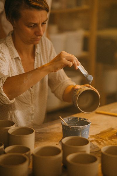 Potter glazing a handmade ceramic mug in a studio — photo by KoolShooters on Pexels