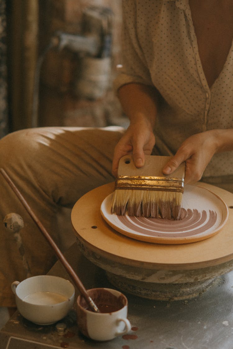 Woman Painting A  Plate Using A Paintbrush