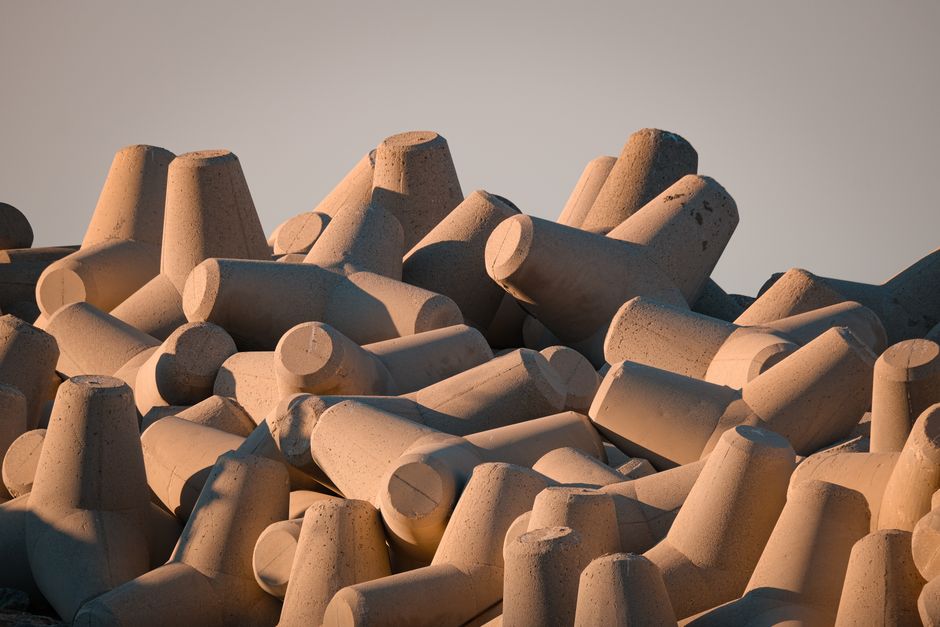 Concrete tetrapods stacked on a seawall, bathed in warm sunset light, emphasizing coastal protection. Concrete tetrapods stacked on a seawall, bathed in warm sunset light, emphasizing coastal protection.