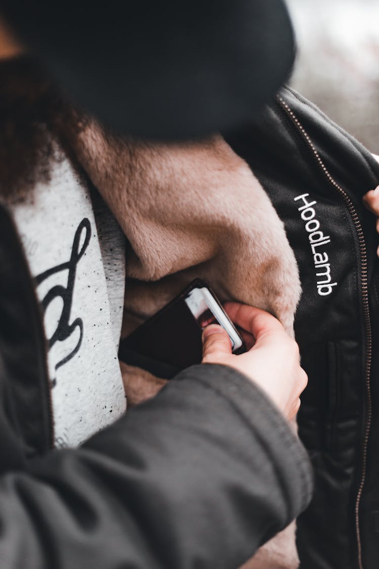 Person Putting Items On The Hidden Pocket Of His Jacket 