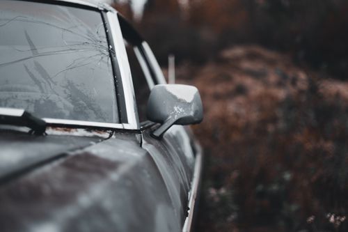 Free Close-up of a weathered, rusted car with a broken windshield and side mirror in an outdoor setting. Stock Photo