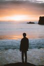Silhouette of man standing on seashore at sunrise