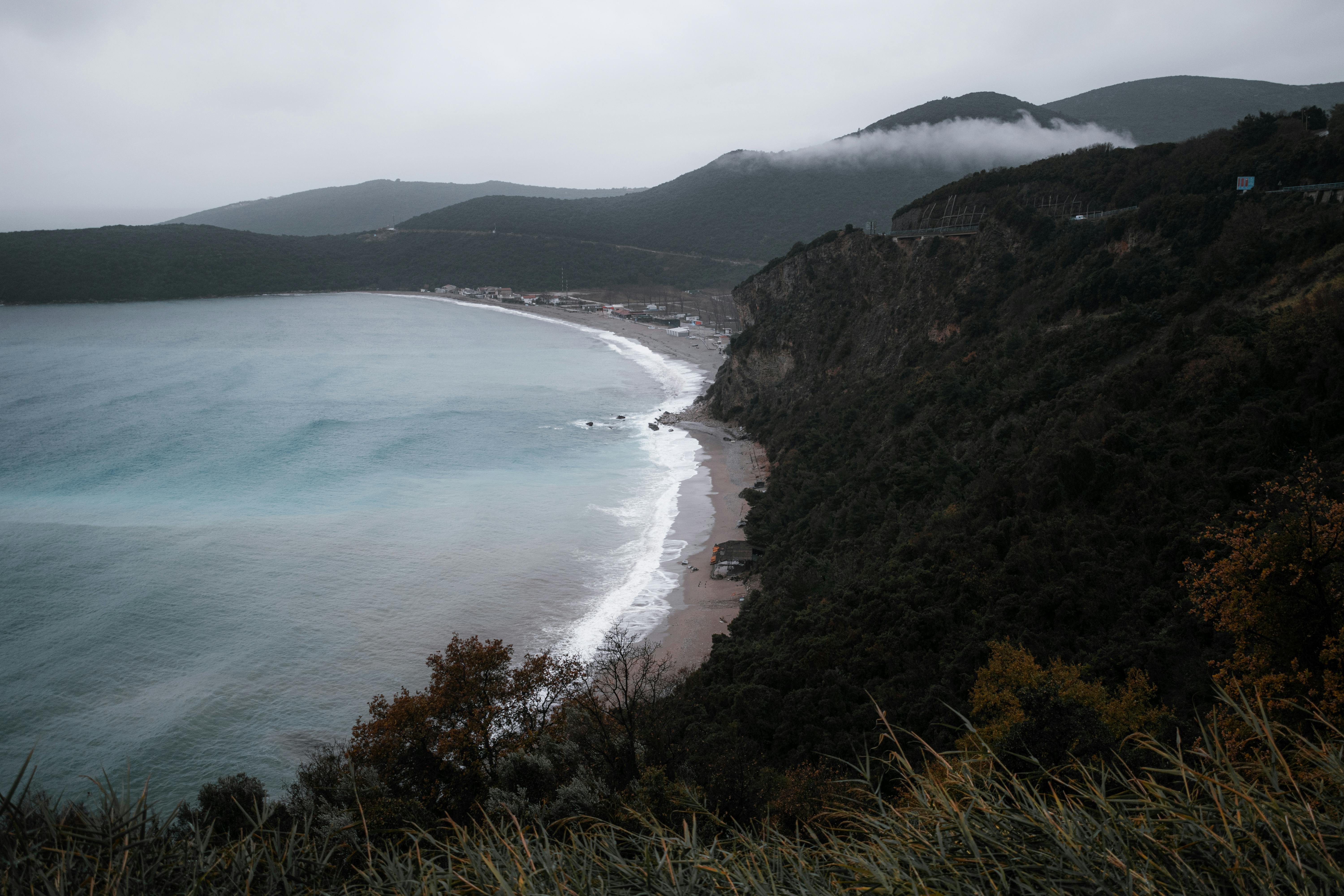Dramatic cliffs and turquoise waters along the coast of Budva, Montenegro on a cloudy day.