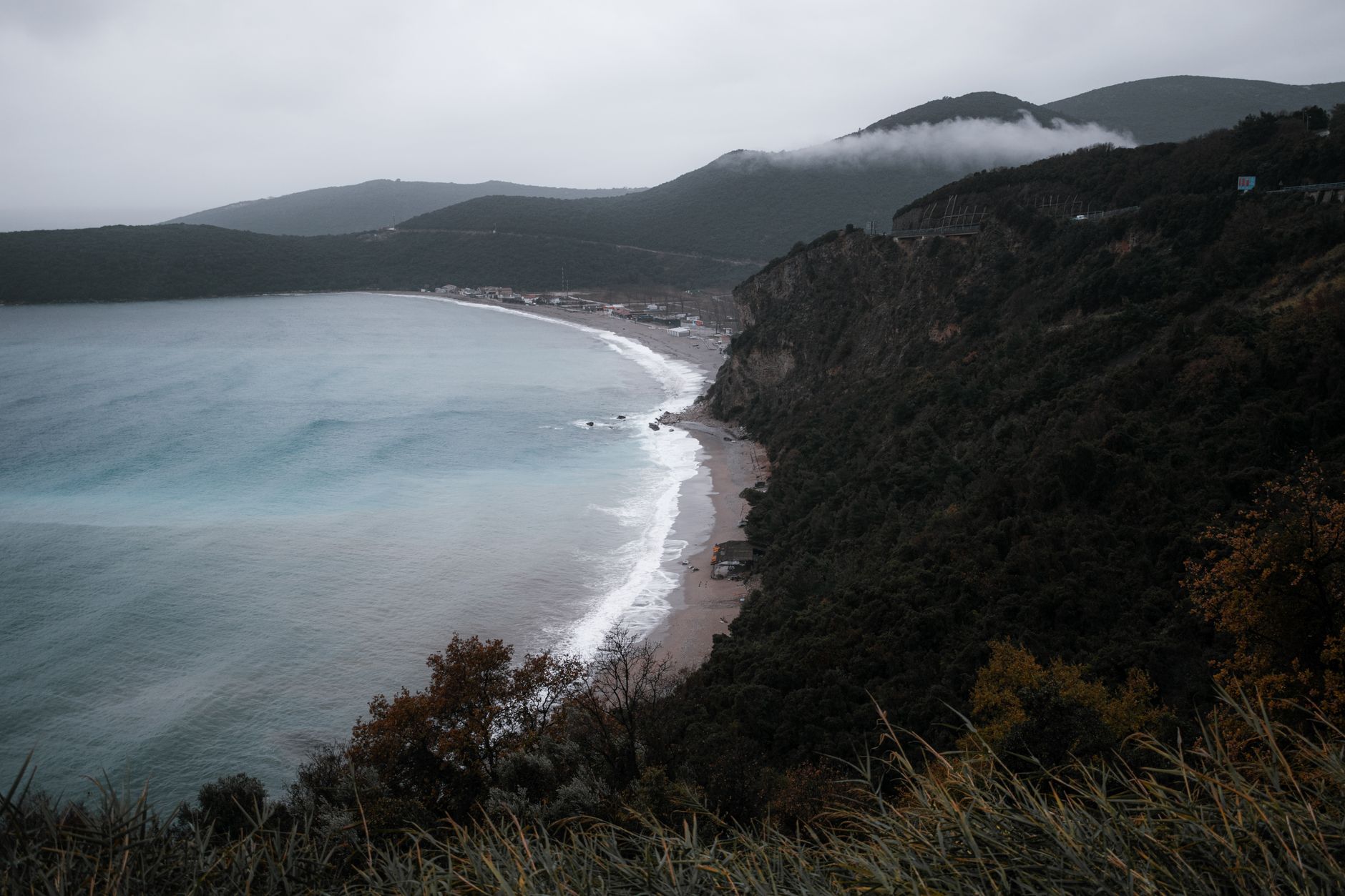 Dramatic cliffs and turquoise waters along the coast of Budva, Montenegro on a cloudy day.