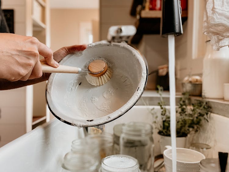 A Person Scrubbing Dirty Plates