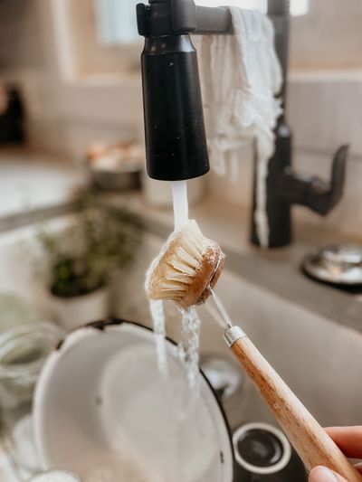 Beech dish brush under running water — photo by Hannah Grapp on Pexels