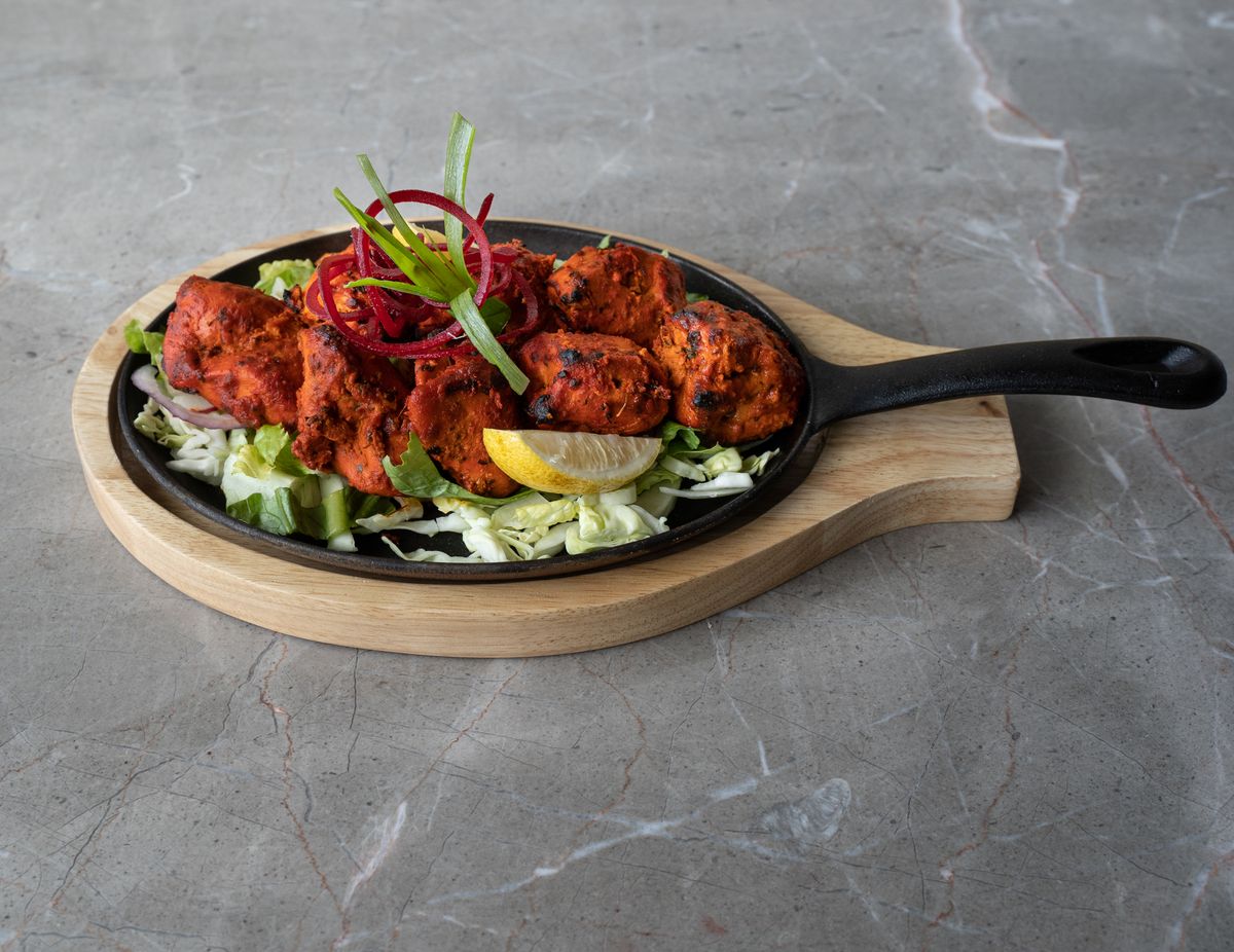 Tandoori chicken arranged on a sizzling platter