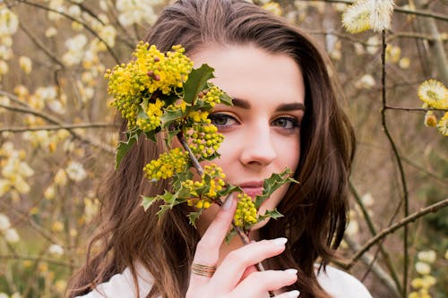 Woman Taking Photo With Holding Yellow Flower Buds at Daytime