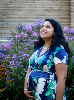 Beautiful pregnant woman in a floral garden, looking up with a joyful expression.