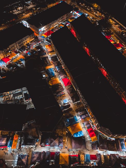 Colorful aerial view of a bustling night market in Kuala Lumpur, showcasing vivid stalls and lively atmosphere.