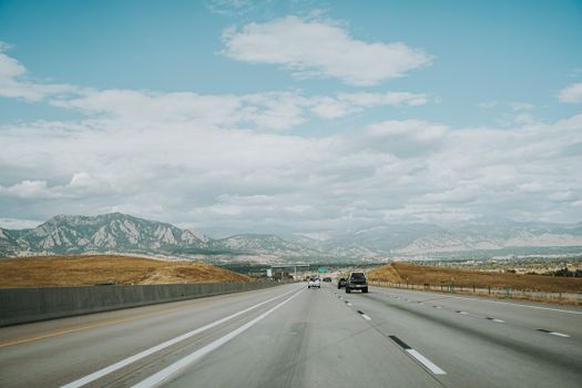 A picturesque highway vista with the Rocky Mountains in Boulder, Colorado under a blue sky.