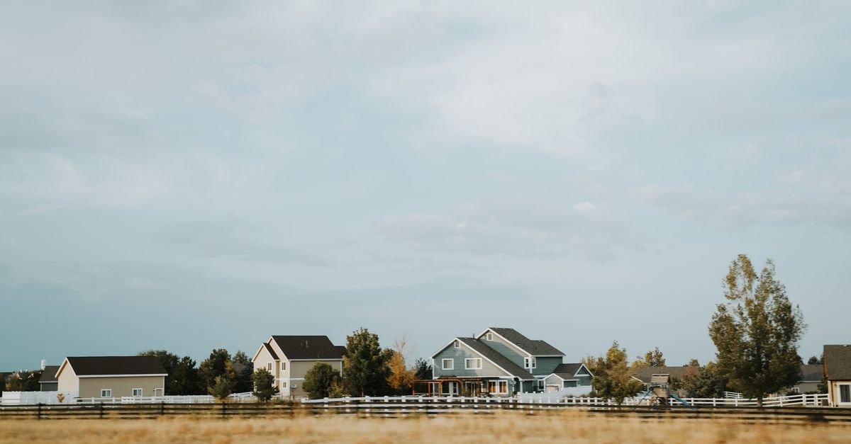 Scenic view of countryside homes with a wooden fence under a wide sky near Denver, Colorado.
