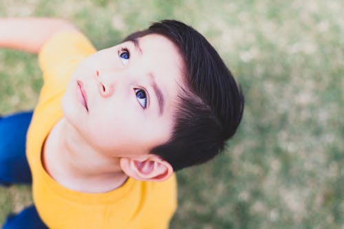 Free Boy Wearing Yellow Crew-neck T-shirt and Blue Bottoms Outfit Looking Above Stock Photo
