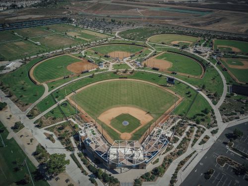 Free Explore a comprehensive aerial shot of interconnected baseball fields and surrounding landscape. Stock Photo