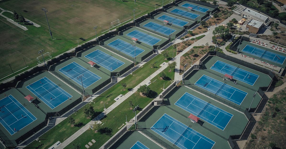 Aerial shot of numerous tennis courts in a recreational park during the day.