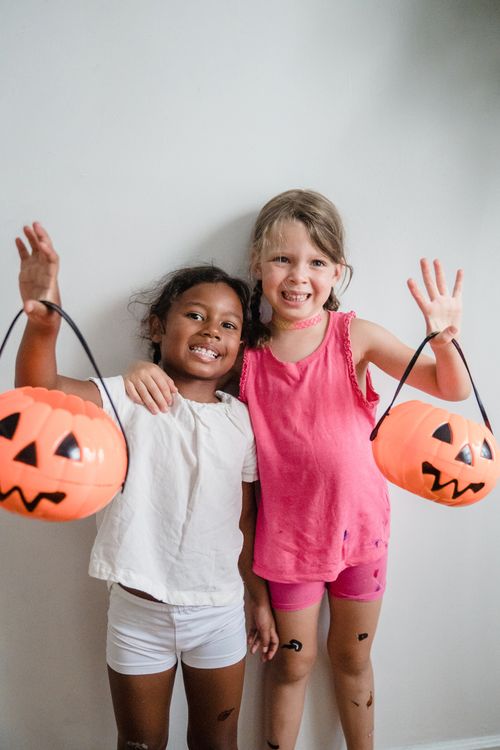 Free Two smiling children holding pumpkin buckets, ready for Halloween fun. Stock Photo