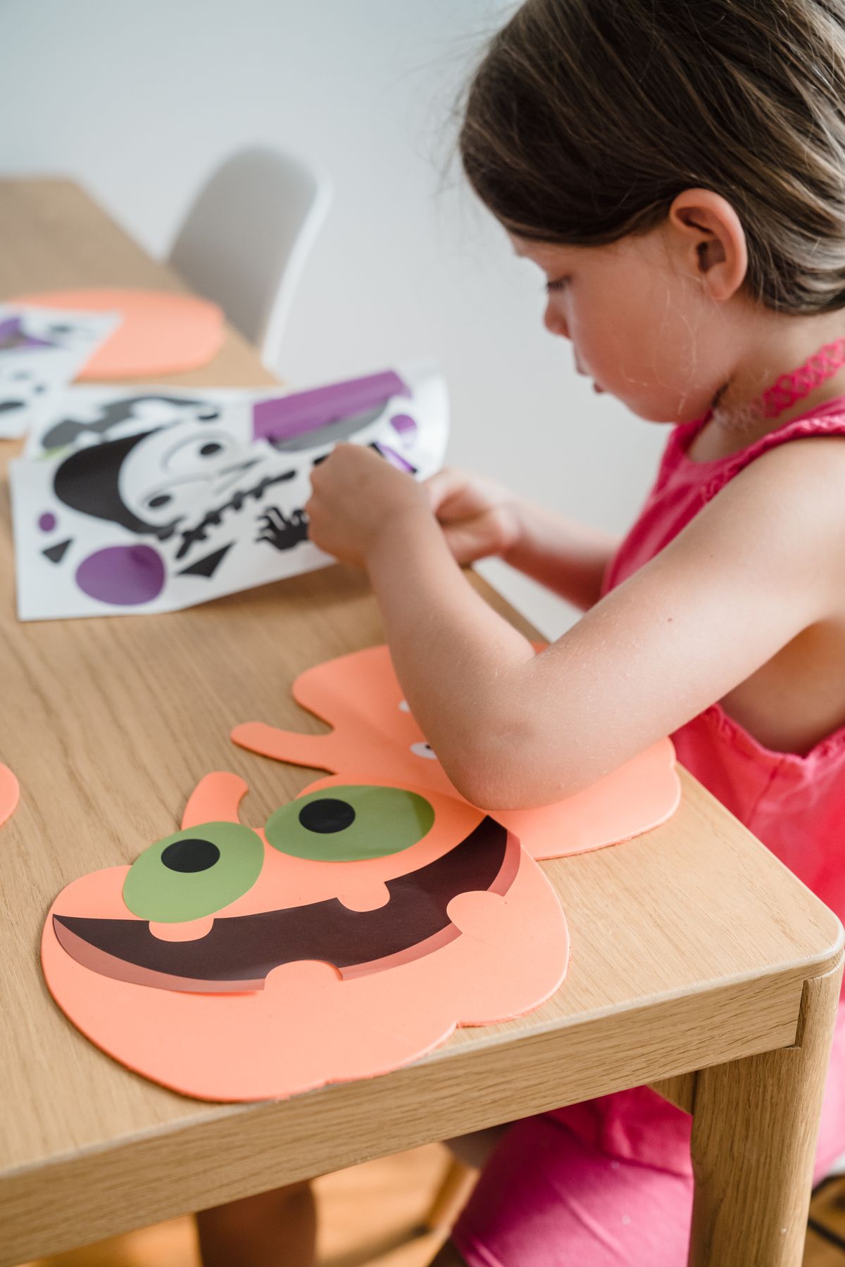 Young girl assembling Halloween paper decorations indoors