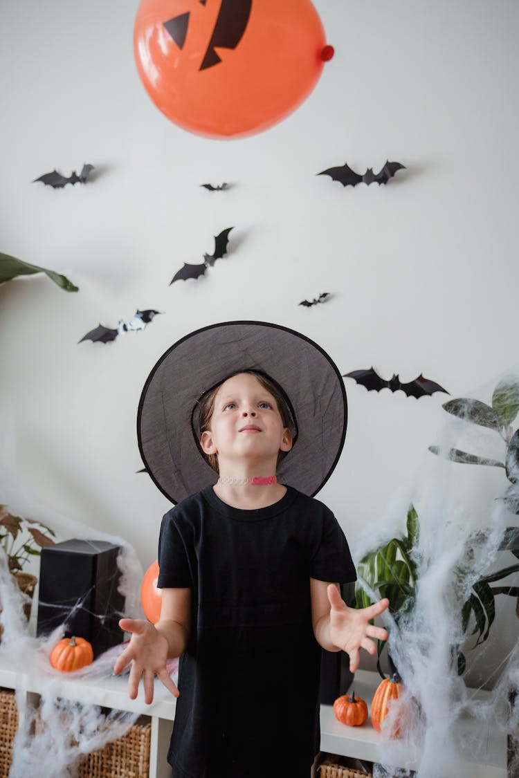 Young Kid In Witch Hat Looking At Flying Balloon