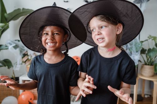 Free Smiling young girls wearing witch hats for Halloween indoors, adding a festive touch. Stock Photo