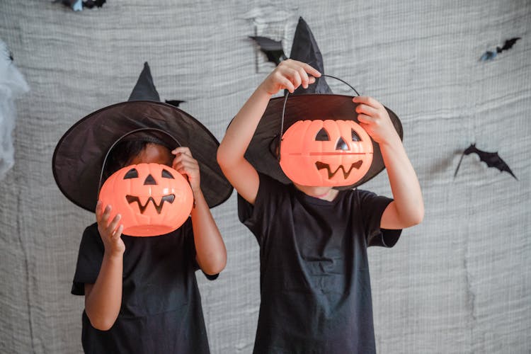 Two Girls Covering Faces With Pumpkins