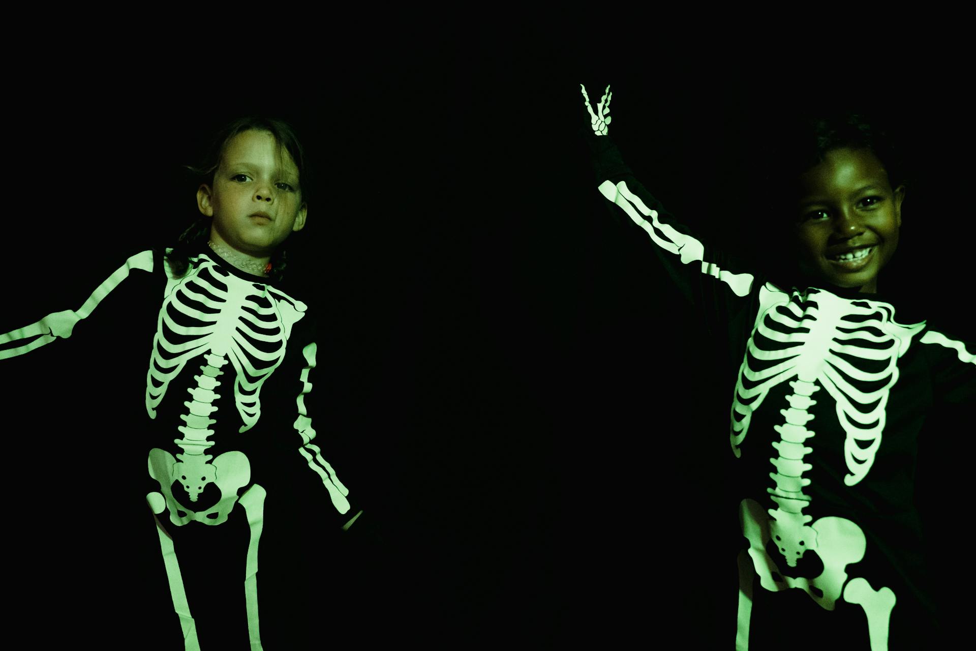 To kids in skeleton costumes under green light