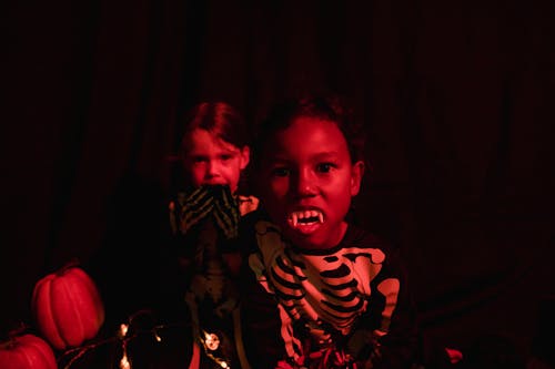 Two kids dressed as skeletons in red light