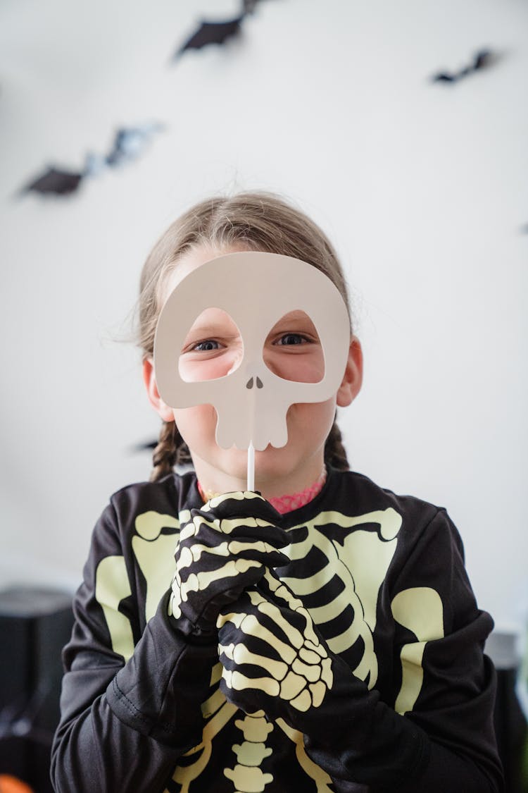 Young Girl Holding Skull On Stick And Looking At Camera