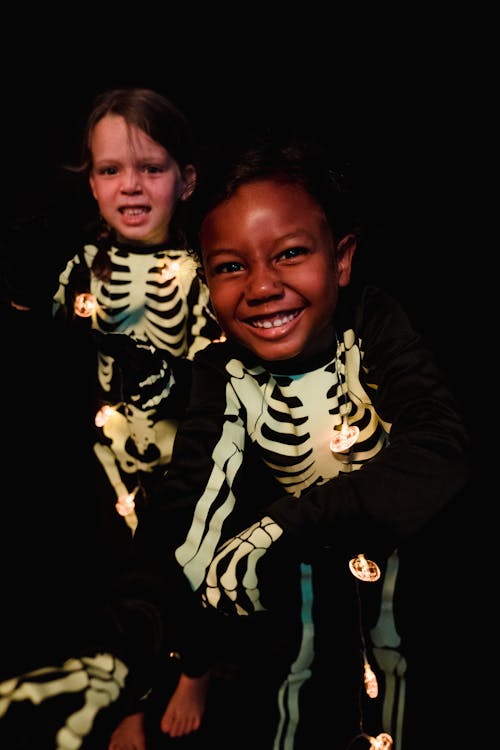 Two kids smiling in skeleton costumes