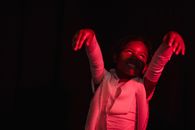 Girl wearing mummy costume and scaring in red-lighted room with hands in front