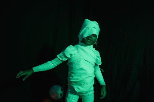 Free Child wearing a mummy costume enjoys halloween fun against a dark background. Stock Photo