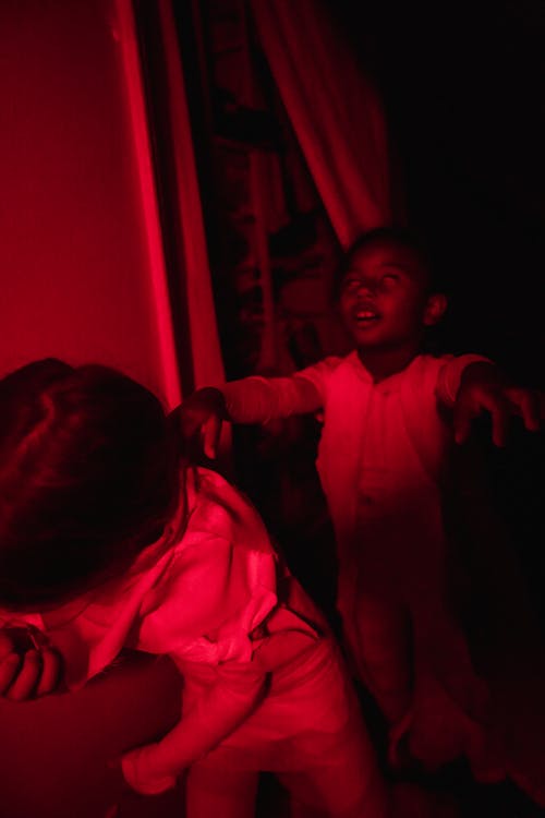 Free Boy in red-lighted room wearing mummy costume and pretending Stock Photo