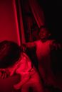 Boy in red-lighted room wearing mummy costume and pretending